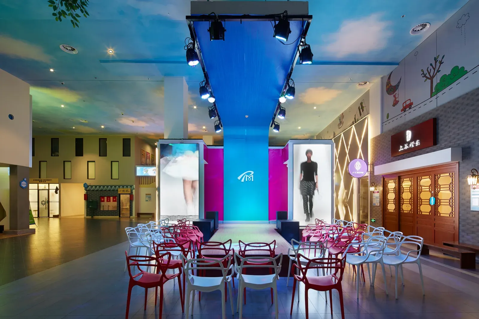 Open hall with a stage and seating framed by shopfronts