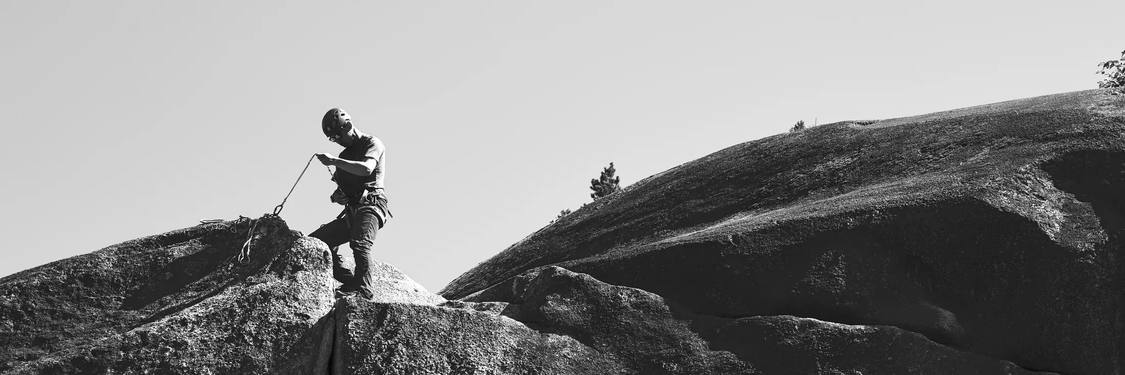 Climber coiling a rope on a granite dome